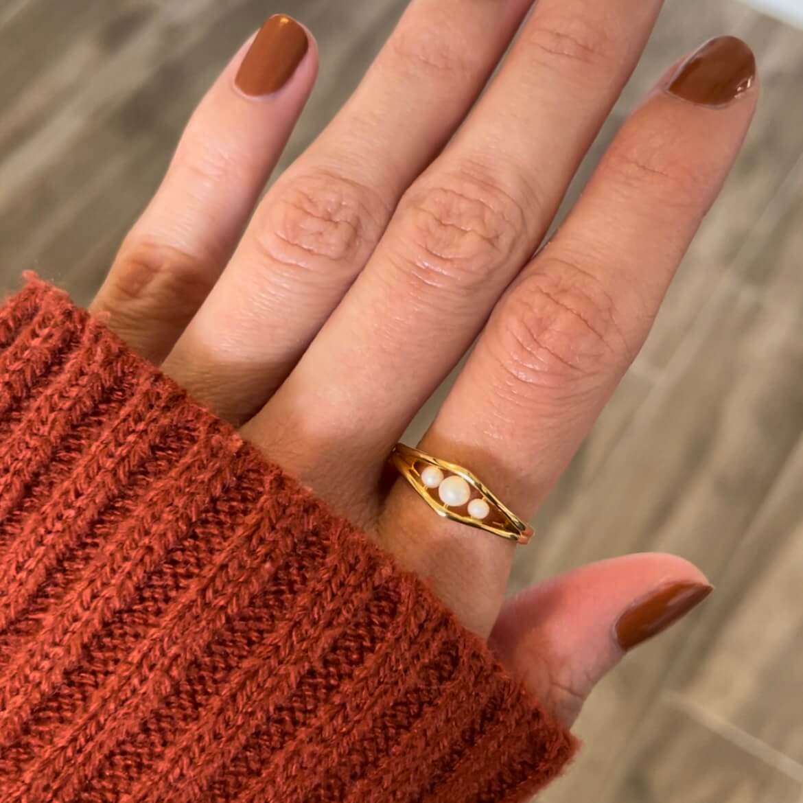 A gold Allure three pearl fidget ring worn on a finger, highlighting the pearl's luster, worn for anxiety and stress relief