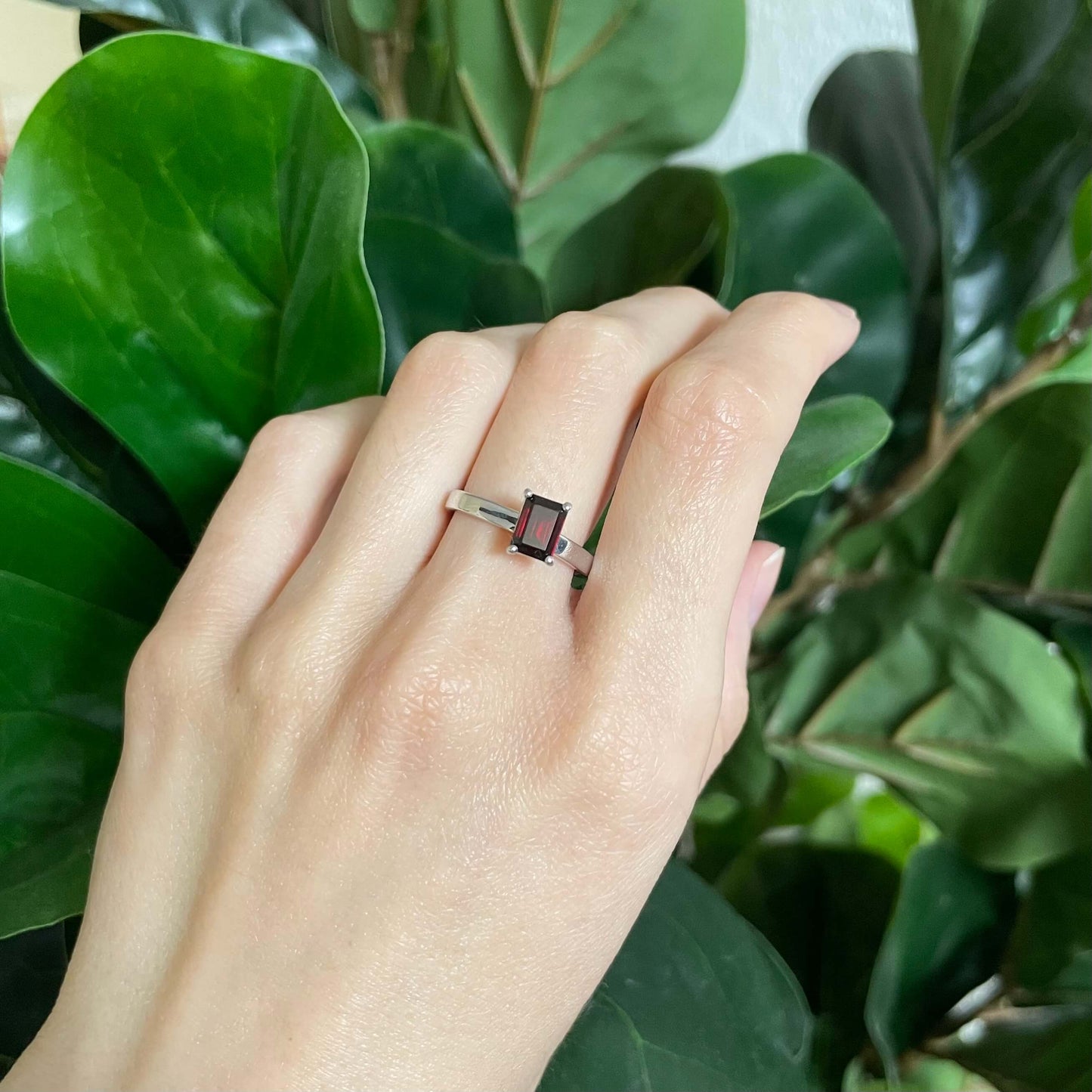 A silver red charmed garnet fidget ring worn on a finger, highlighting the dark red gemstone's vibrant color