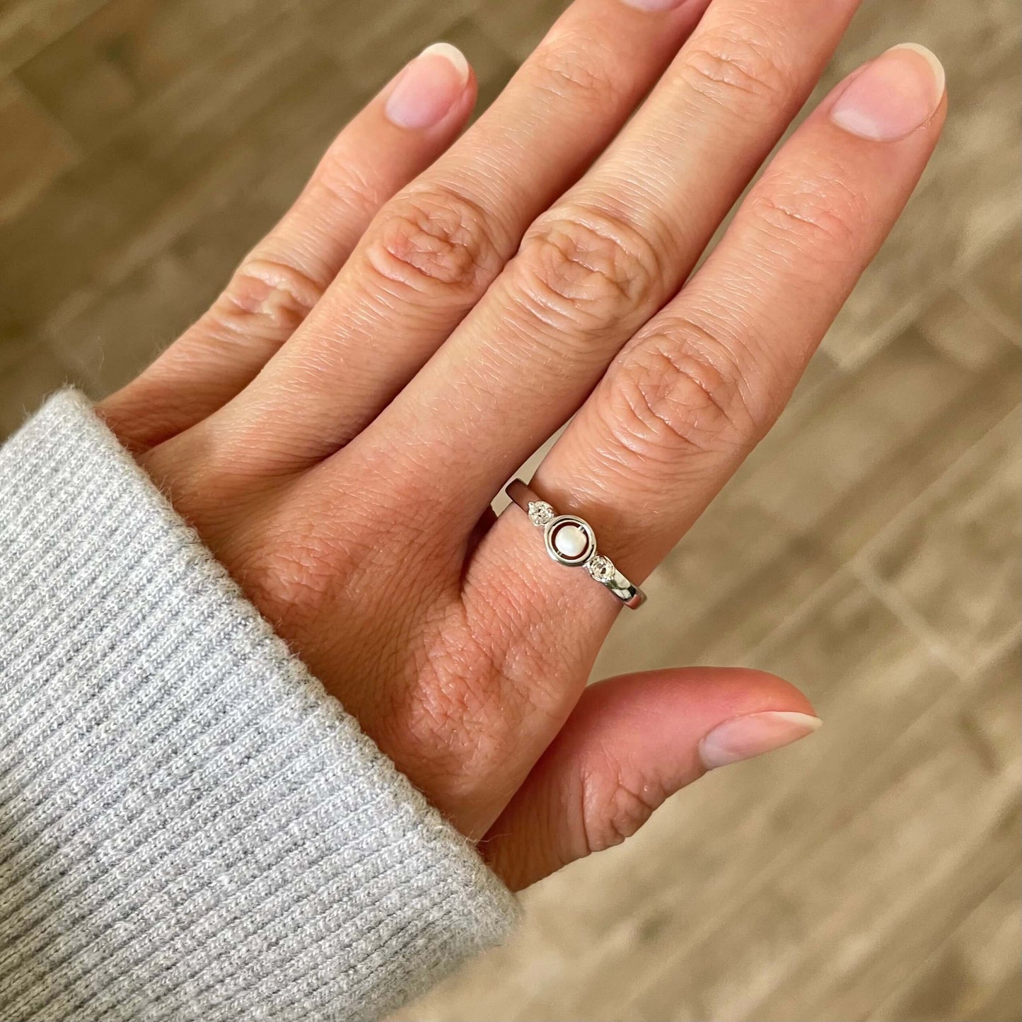 A silver Mindful pearl fidget ring worn on a finger, highlighting the pearl's luster, worn for anxiety and stress relief
