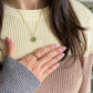 A Grace green aventurine fidget necklace in gold worn with the pearl fidget ring