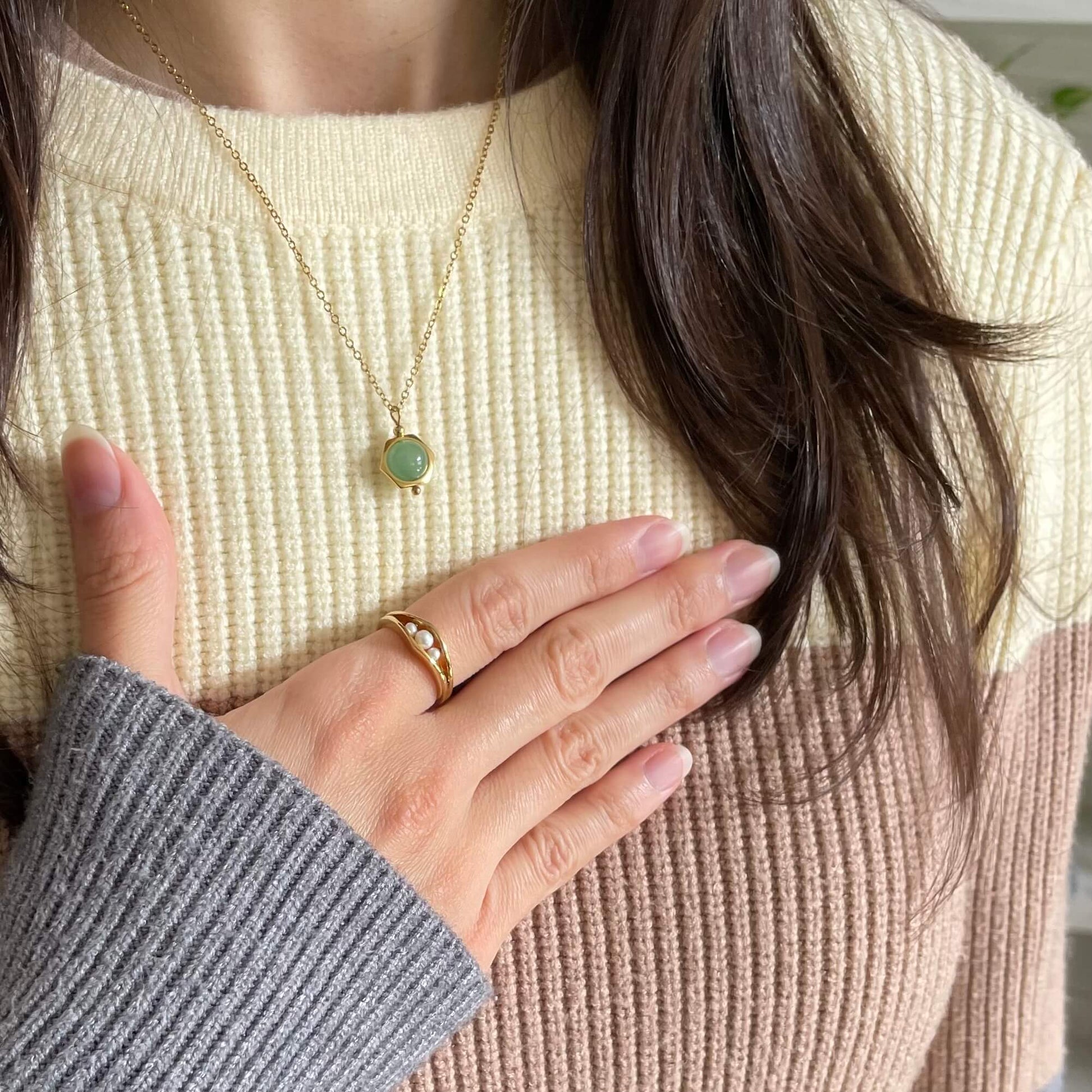 A Grace green aventurine fidget necklace in gold worn with the pearl fidget ring